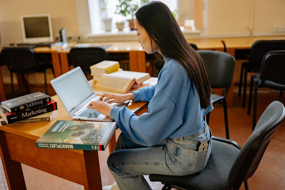 student studying online laptop library desk