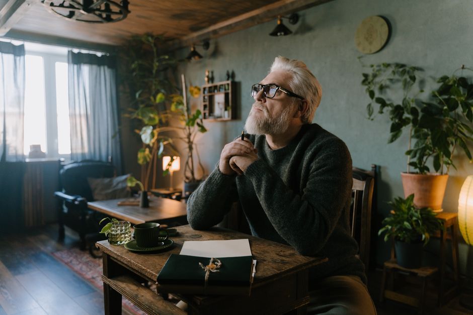 person writing on desk looking thoughtful