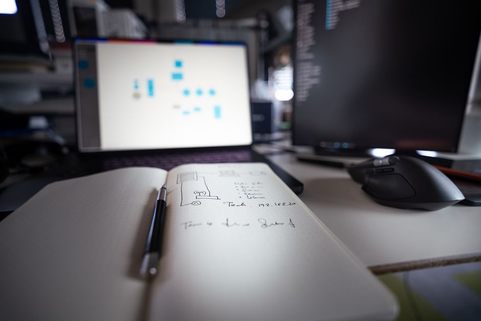 developer writing code on notebook computer office desk