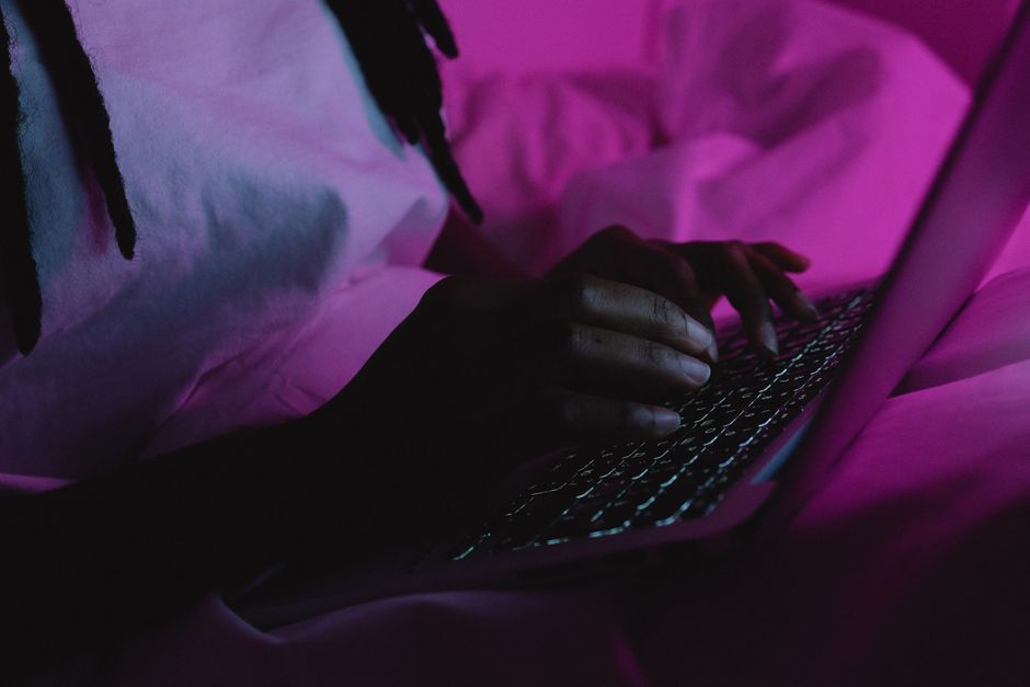 person typing laptop keyboard late night room