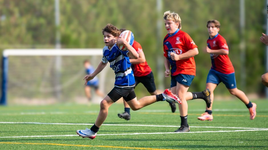 rugby player running with ball outdoor pitch